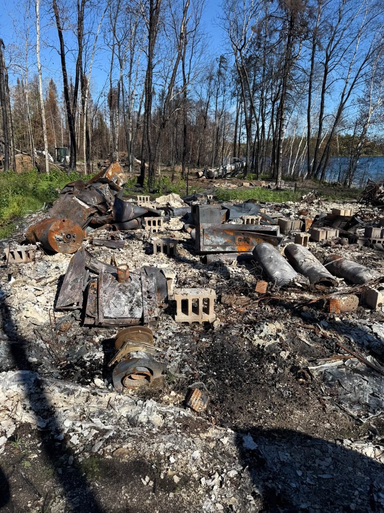 Fire-damaged lot undergoing debris clearing and ground preparation for building pad in Northwestern Ontario